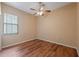 This bedroom features hardwood floors, a ceiling fan, and a window for natural light at 9104 Water Hazard Dr, Hudson, FL 34667