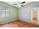 This bedroom features hardwood floors, a ceiling fan, and a window for natural light at 9104 Water Hazard Dr, Hudson, FL 34667