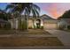 Charming home featuring a two-car garage, a well-manicured lawn, and mature palm trees at 9104 Water Hazard Dr, Hudson, FL 34667