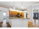 Stylish kitchen featuring wood cabinets, a breakfast bar, modern backsplash, and views into the main entry at 9104 Water Hazard Dr, Hudson, FL 34667