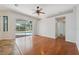Bright living room featuring hardwood floors, ceiling fan, and sliding glass doors to the pool area at 9104 Water Hazard Dr, Hudson, FL 34667