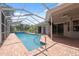 This pool area features a screened enclosure, brick pavers, and a clear blue pool at 9104 Water Hazard Dr, Hudson, FL 34667