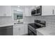 Bright kitchen features white cabinets, stainless steel appliances, and a view of the swimming pool at 9141 Greenbriar Ln, Port Richey, FL 34668