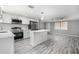 Modern kitchen with stainless steel appliances and white cabinetry adjacent to the living room at 9141 Greenbriar Ln, Port Richey, FL 34668