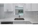 Close-up of kitchen sink with a view to the swimming pool and modern white tile backsplash at 9141 Greenbriar Ln, Port Richey, FL 34668