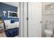 Inviting view of the bathroom, featuring a white toilet and shelving adjacent to bedroom with blue accent wall at 9400 New Orleans Dr, Weeki Wachee, FL 34613