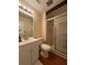 Bright bathroom with wood flooring, sink vanity, a shower with sliding glass doors and toilet at 947 Village Dr, Brooksville, FL 34601