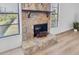 Detailed view of the stone fireplace and hearth complemented by light-filled windows and wood-style flooring at 9970 Eagles Point Cir # 3, Port Richey, FL 34668