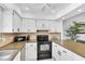 Well-lit kitchen featuring white cabinets, tiled backsplash and a black range offering a practical design at 9970 Eagles Point Cir # 3, Port Richey, FL 34668