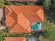 Aerial view of the home features a terra cotta roof, lush landscaping and a screened-in pool area at 1033 Tuscany Dr, Trinity, FL 34655