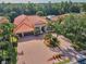 Aerial view of home with lush backyard, mature trees, three car garage, and circular driveway at 1033 Tuscany Dr, Trinity, FL 34655