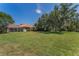Large grassy backyard featuring mature trees and an enclosed patio at 1033 Tuscany Dr, Trinity, FL 34655