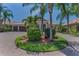 Charming home with a circular driveway and lush tropical landscaping including palm trees and flowering bushes at 1033 Tuscany Dr, Trinity, FL 34655