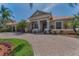 Elegant single-story home with a tile roof, mature landscaping, and a brick paved driveway at 1033 Tuscany Dr, Trinity, FL 34655