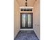 Elegant glass front double door with textured stone entryway and overhead transom window at 1033 Tuscany Dr, Trinity, FL 34655