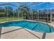 Sparkling pool with screened-in enclosure offers privacy, with lush landscaping and bright blue sky overhead at 1033 Tuscany Dr, Trinity, FL 34655