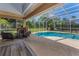 Sparkling pool surrounded by a screened-in lanai, featuring a stone fireplace and comfortable seating area at 1033 Tuscany Dr, Trinity, FL 34655