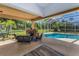 Inviting outdoor living space with a stone fireplace, comfortable seating, and a sparkling pool at 1033 Tuscany Dr, Trinity, FL 34655