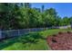Well-maintained backyard with green lawn, garden beds, and white fence offers a private retreat at 12800 Solola Way, Trinity, FL 34655