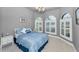 Cozy bedroom with a blue patterned bedspread, bay windows with shutters, and neutral carpeting at 12800 Solola Way, Trinity, FL 34655
