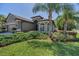 Well-manicured front yard with lush greenery, palm trees, and a charming home exterior at 12800 Solola Way, Trinity, FL 34655