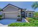 Charming home featuring a gray stucco exterior, attached two-car garage, and meticulously manicured front yard landscaping at 12800 Solola Way, Trinity, FL 34655