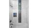 Elegant shower with white marble-style tiles and a decorative accent tile strip and niche at 12800 Solola Way, Trinity, FL 34655