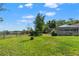Large grassy backyard featuring a full fence, mature trees, and views of the screened in lanai at 13469 Pia Ct, Spring Hill, FL 34609