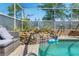 Close-up of a screened-in pool featuring a waterfall, lush greenery, and patio seating at 13469 Pia Ct, Spring Hill, FL 34609