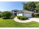 Well-maintained home featuring lush landscaping, a brick driveway, and a two-car garage, exuding curb appeal at 14105 Agua Clara Dr, Hudson, FL 34667