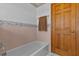 Bathroom with pink tiling around the tub, a towel rack, and wooden door at 15535 Allmand Dr, Hudson, FL 34667