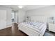 Cozy bedroom featuring a white framed bed, hardwood floors and a view into the ensuite bathroom at 18441 Whitacre Cir, Hudson, FL 34667
