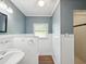 This bathroom features wainscoting, white walls, gray trim, laminate flooring, a sink, a toilet and a window at 196 Lark Ave, Brooksville, FL 34601