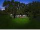 Night view of a charming single-story home nestled among mature trees, with a long driveway at 196 Lark Ave, Brooksville, FL 34601