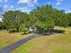 Aerial view of a charming single-story home with mature trees, carport, and long driveway at 196 Lark Ave, Brooksville, FL 34601