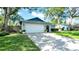 Charming single-story home featuring a manicured lawn, mature shade trees, and an attached two-car garage at 2116 Karan Way, Clearwater, FL 33763