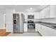 The renovated kitchen has modern stainless steel appliances, granite countertops, and updated white cabinets with hardware at 2116 Karan Way, Clearwater, FL 33763