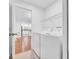 Bright laundry room with white washer and dryer, wire shelving, and view into updated kitchen at 2116 Karan Way, Clearwater, FL 33763