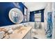 Bright bathroom with blue walls, featuring a unique shower curtain and an artistic round mirror at 2254 Coachman Rd, Spring Hill, FL 34608
