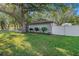 A single-story home's backyard and side yard with grass, a fence and trees at 2254 Coachman Rd, Spring Hill, FL 34608