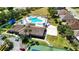 Aerial view of the community clubhouse, pool, tennis court and beach volleyball court with lush landscaping at 2325 Pleasant Hill Ln, Holiday, FL 34691