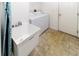 Bright laundry room features a utility sink and modern washer and dryer units at 2325 Pleasant Hill Ln, Holiday, FL 34691
