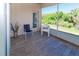 Relaxing screened patio with stylish chairs and wood-look tile flooring overlooking a lush green landscape at 2325 Pleasant Hill Ln, Holiday, FL 34691