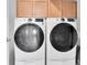 Modern laundry room equipped with front loading washer and dryer units and upper cabinetry at 2815 Dudley Ave, Odessa, FL 33556