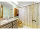 Bathroom with a yellow shower and sink, a dark vanity, and a flowered shower curtain at 3029 Harrow Rd, Spring Hill, FL 34606