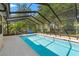 Cool off in this refreshing screened-in pool with a patio and lush landscaping in the background at 3029 Harrow Rd, Spring Hill, FL 34606