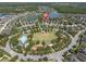 Aerial view of a suburban neighborhood with a large grassy common area, pool, and lake at 3057 Riders Pass, Odessa, FL 33556