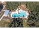 Aerial view of a community pool featuring ample seating, a modern design, and bordered by mature trees at 3057 Riders Pass, Odessa, FL 33556