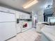 Efficient kitchen layout with white appliances, ample counter space, and modern tile flooring for cooking convenience at 3074 Cara Ct, Palm Harbor, FL 34684