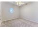 Cozy bedroom featuring neutral carpeting, a unique round window, and a ceiling fan for a comfortable space at 4044 Chesterfield Dr, Spring Hill, FL 34609